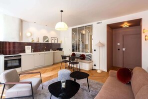 A modern living room with a sofa, chairs, a coffee table, and a dining area with a table and chairs.