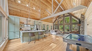 A spacious kitchen with a central island, wooden ceiling, and large windows. - Romantic Cabin Swings | Private Sauna & Hot Tub! (Broken Bow)