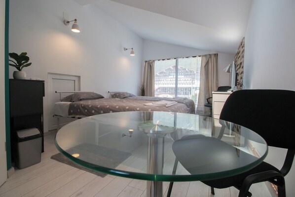 Relax in this inviting bedroom with a neatly made bed, glass-top table, and comfortable office chair.