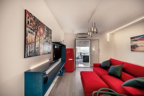Un soggiorno moderno con un divano rosso, una televisione a schermo piatto e opere d'arte alle pareti.