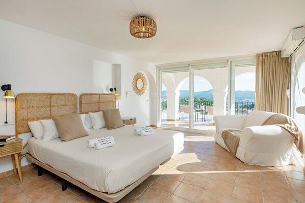 Un dormitorio amplio con una cama grande, un sofá y vistas al exterior.
