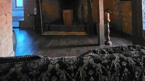 A room with a fireplace, wooden beams, and a patterned rug. - Hermannstein Castle - Knights' Hall (Wetzlar)