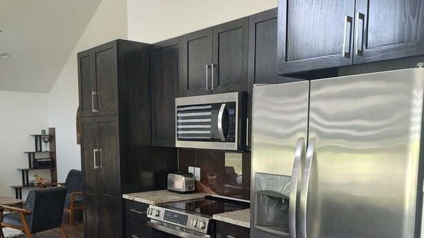 A modern kitchen with dark wood cabinets, stainless steel appliances, and a wooden floor. - 2-bedroom, pet friendly home with great amenities. It will be your happy place (Holly Lake Ranch)
