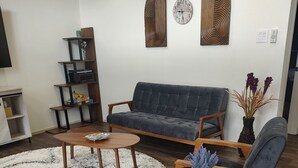 A modern living room with a grey sofa, two armchairs, a coffee table, and a decorative clock on the wall. - 2-bedroom, pet friendly home with great amenities. It will be your happy place (Holly Lake Ranch)