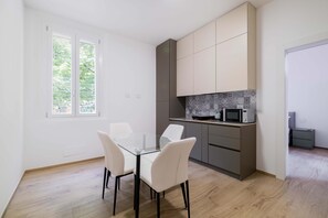Eine moderne Küche mit weißen Schränken, einem Glastisch und einer Mikrowelle.