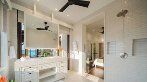 Un bagno moderno con un mobile lavabo bianco, una ventola a soffitto e una zona doccia.