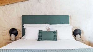 A bed with white bedding, a teal headboard, and two black lamps on either side.
