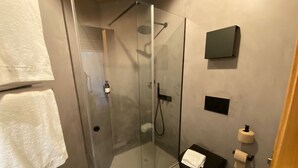 Une salle de bain moderne avec une douche à parois de verre, des toilettes noires et un porte-serviettes.