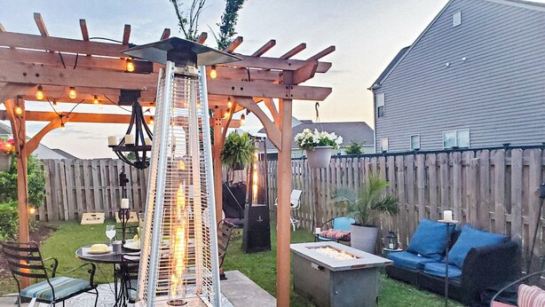 Un patio trasero con pérgola, una chimenea exterior, mobiliario de jardín y valla de madera.