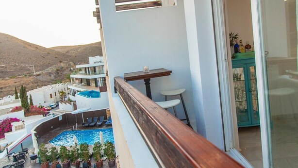 A balcony with a pool, white buildings, and a mountainous backdrop. - Cozy Apartment by the Sea in Carboneras (Carboneras)