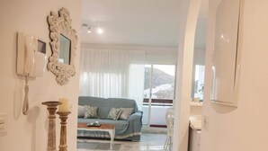 A living room with a sofa, a coffee table, and a view of a snowy landscape through large windows. - Cozy Apartment by the Sea in Carboneras (Carboneras)