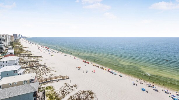 A beach with a boardwalk, beach umbrellas, and a clear view of the ocean. - Tradewinds 1301 Beachfront Top-floor (Orange Beach)