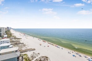 A beach with a boardwalk, beach umbrellas, and a clear view of the ocean. - Tradewinds 1301 Beachfront Top-floor (Orange Beach)
