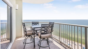 A balcony with a table and chairs, overlooking a beach and the ocean. - Tradewinds 1301 Beachfront Top-floor (Orange Beach)