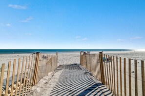 A wooden boardwalk leading to a sandy beach with a clear blue sky. - The Beach Front 601- Affordable Beachfront (Gulf Shores)