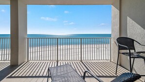 A balcony with a view of the beach, a chair, and a table. - Windward Pointe 804- Sleeps 10 Beachfront Resort Amenities (Orange Beach)