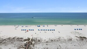 Una playa con hileras de sombrillas azules y una vista despejada del océano.