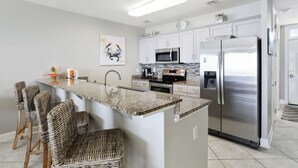 Una cocina moderna con una isla central, electrodomésticos de acero inoxidable y taburetes de bar.