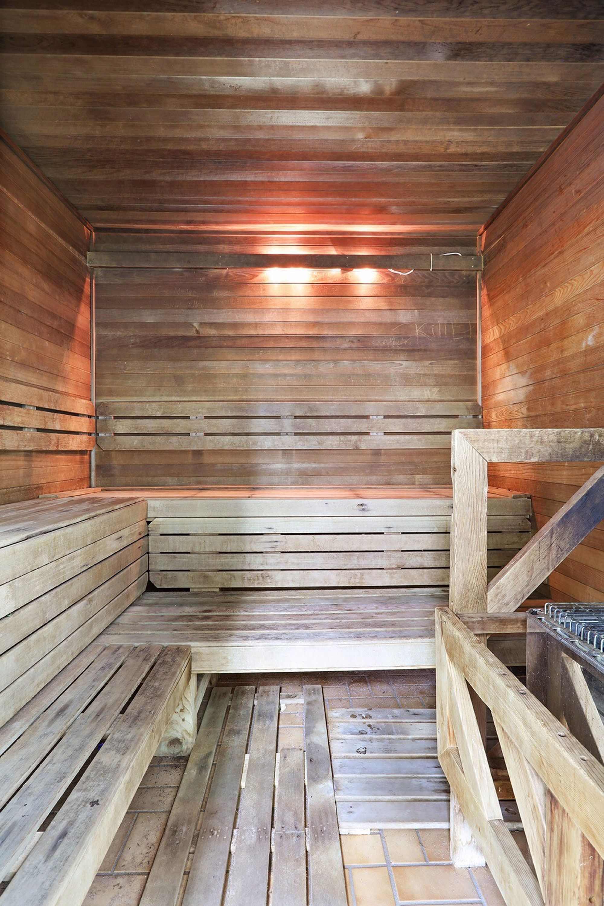 Un sauna avec des bancs en bois et un sol carrelé.