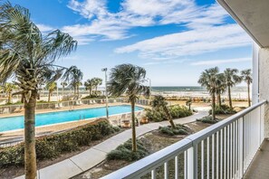 A pool area with palm trees, a view of the beach, and a clear sky. - Ssbrc 4210- Direct Beachfront Stunning Views (Orange Beach)