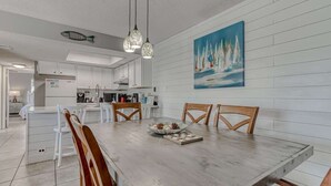 Een moderne keuken met witte kasten, een eettafel met houten stoelen en hanglampen.