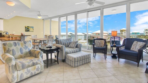 A spacious living area with a large window, ceiling fan, and a dining table. - Sanibel 306- Beach Access Gulf Views Sun Deck (Gulf Shores)
