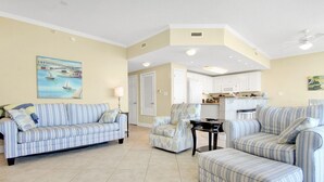 A living room with striped sofas, a coffee table, and a painting of a bridge. - Sanibel 306- Beach Access Gulf Views Sun Deck (Gulf Shores)