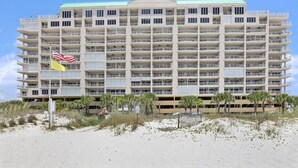 A multi-story hotel with a symmetrical facade, numerous balconies, and a flat roof. - Regency Isle 711 2 BR 2 5 BA Sleep 8 Gulf-front (Orange Beach)