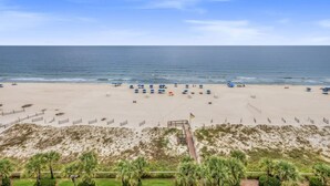 A beach with a clear view of the ocean, a sandy area with umbrellas, and a pathway leading to a flag. - Regency Isle 711 2 BR 2 5 BA Sleep 8 Gulf-front (Orange Beach)