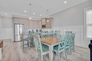 Une cuisine moderne équipée d’appareils électroménagers en acier inoxydable, d’une table à manger en bois et de chaises de couleur turquoise.