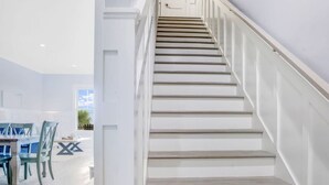 Una escalera con paredes blancas y escalones de madera que conduce a una puerta.