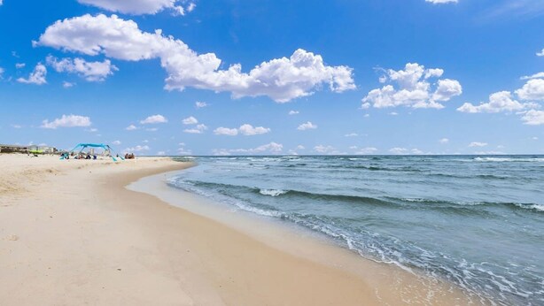 Una playa con cielo despejado y algunas nubes.