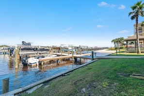 Un puerto deportivo con barcos amarrados, una zona ajardinada y un edificio con una palmera.