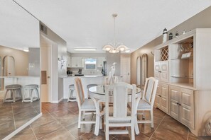 A modern kitchen with white cabinetry, a central island, and a dining area with a round table and chairs.