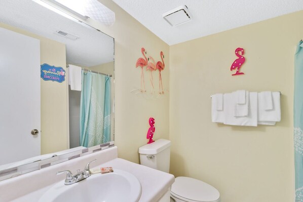 A bathroom with a white sink, a mirror, a toilet, and a shower curtain. - Las Palmas 114- Pool BBQ Short Walk to Beach (Gulf Shores)