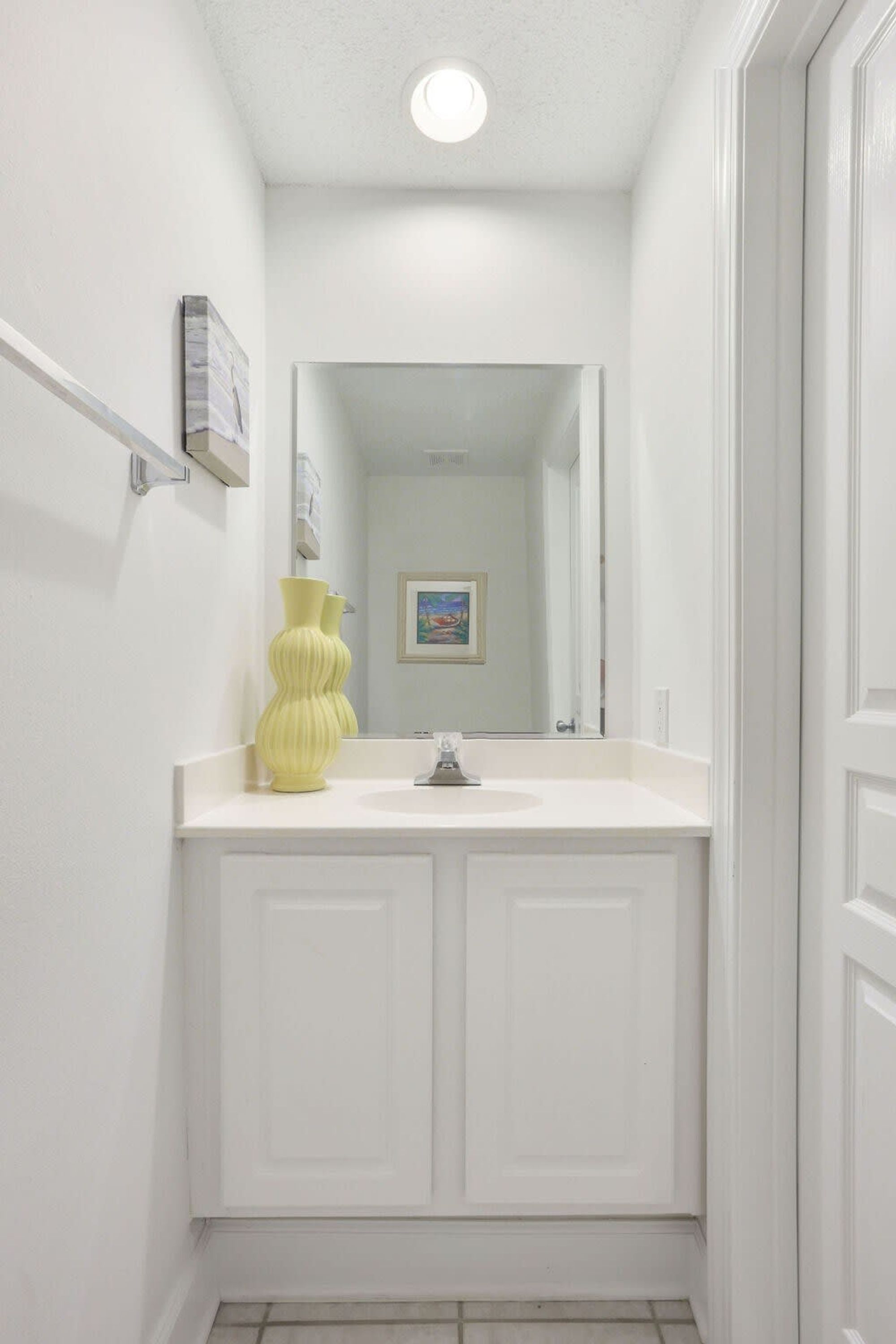 Un bagno con un mobile lavabo bianco, un vaso giallo e un quadro appeso alla parete.