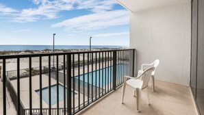 Un balcón con vista a una piscina y una playa.