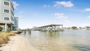Une propriété située au bord de l’eau, dotée d’un quai couvert qui s’avance sur l’eau, d’une plage de sable et d’un bâtiment à plusieurs étages.