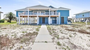 A two-story beachfront house with a covered front porch and a balcony. - Lagoon Time Beach Home- Elevator Beach Access (Gulf Shores)