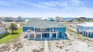 A beachfront property with a large house featuring a balcony and a covered porch. - Lagoon Time Beach Home- Elevator Beach Access (Gulf Shores)