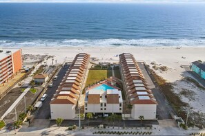 An aerial view of a beachfront hotel with a central building and two symmetrical wings, a parking area, and a beach in the background. - Gulfside Townhome 32 Beachfront Townhouse w Pool (Gulf Shores)
