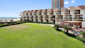 A hotel with multiple balconies overlooking a beach, a pool area, and a well-maintained lawn. - Gulfside Townhome 32 Beachfront Townhouse w Pool (Gulf Shores)