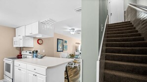 A kitchen with white cabinets, a microwave, and a dining area with a table and chairs. - Gulfside Townhome 32 Beachfront Townhouse w Pool (Gulf Shores)