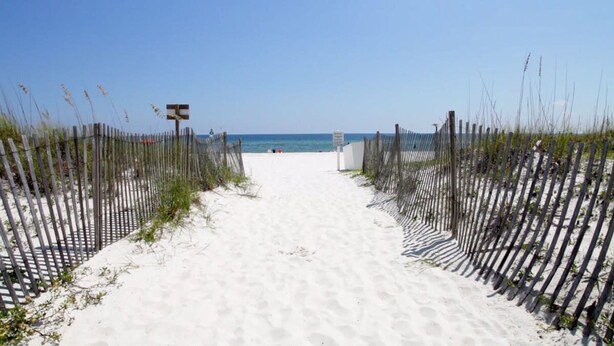 A sandy beach path leading to the ocean, flanked by wooden fences. - Gulfside Townhome 32 Beachfront Townhouse w Pool (Gulf Shores)