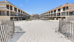 A beachfront hotel with multiple balconies, a sandy beach in front, and a clear blue sky. - Gulfside Townhome 32 Beachfront Townhouse w Pool (Gulf Shores)