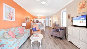 A living room with a sofa, armchair, and coffee table, connected to a kitchen and dining area. - Grand Pointe 502- Gulf-front Water on 2 Sides (Orange Beach)