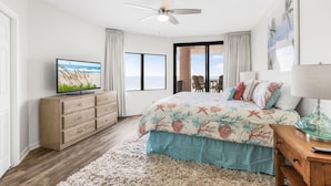 A bedroom with a bed, a TV, a ceiling fan, a window, and a door leading to a balcony. - Four Seasons 502-e Pier Newly Remodeled (Orange Beach)