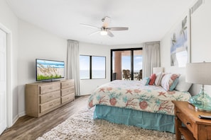 A bedroom with a bed, a television, a ceiling fan, and a view of the outdoors. - Four Seasons 502-e Pier Newly Remodeled (Orange Beach)