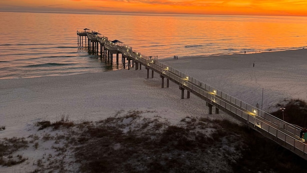A pier extending into a calm sea at sunset. - Four Seasons 502-e Pier Newly Remodeled (Orange Beach)