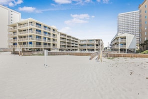 A beachfront hotel with multiple balconies, a sandy beach, and a clear blue sky. - Gulf Village 214- Close to the Hangout Beachfront (Gulf Shores)